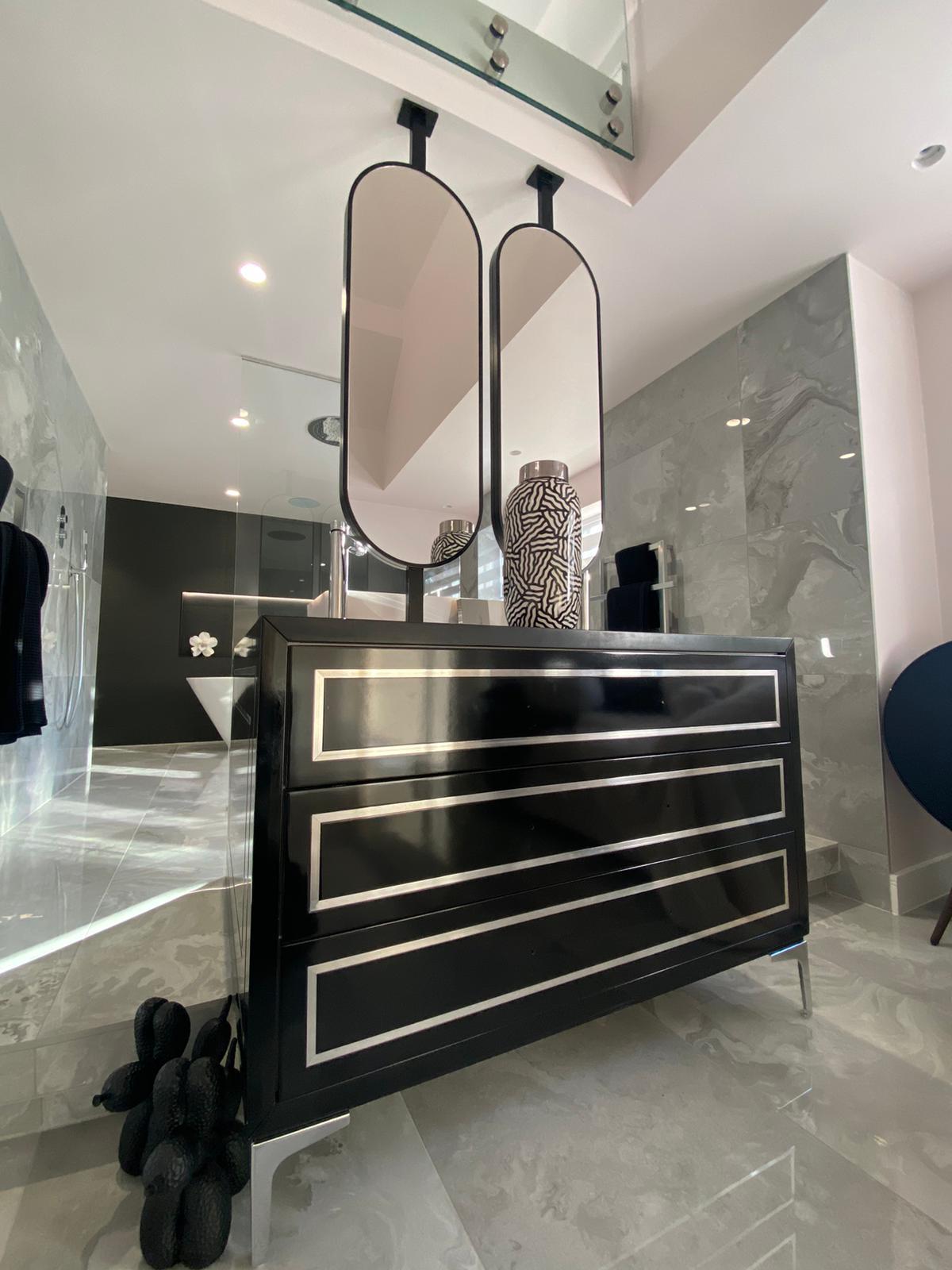 Close view of a gloss black vanity unit with chrome inlay drawer fronts and polished chrome feet