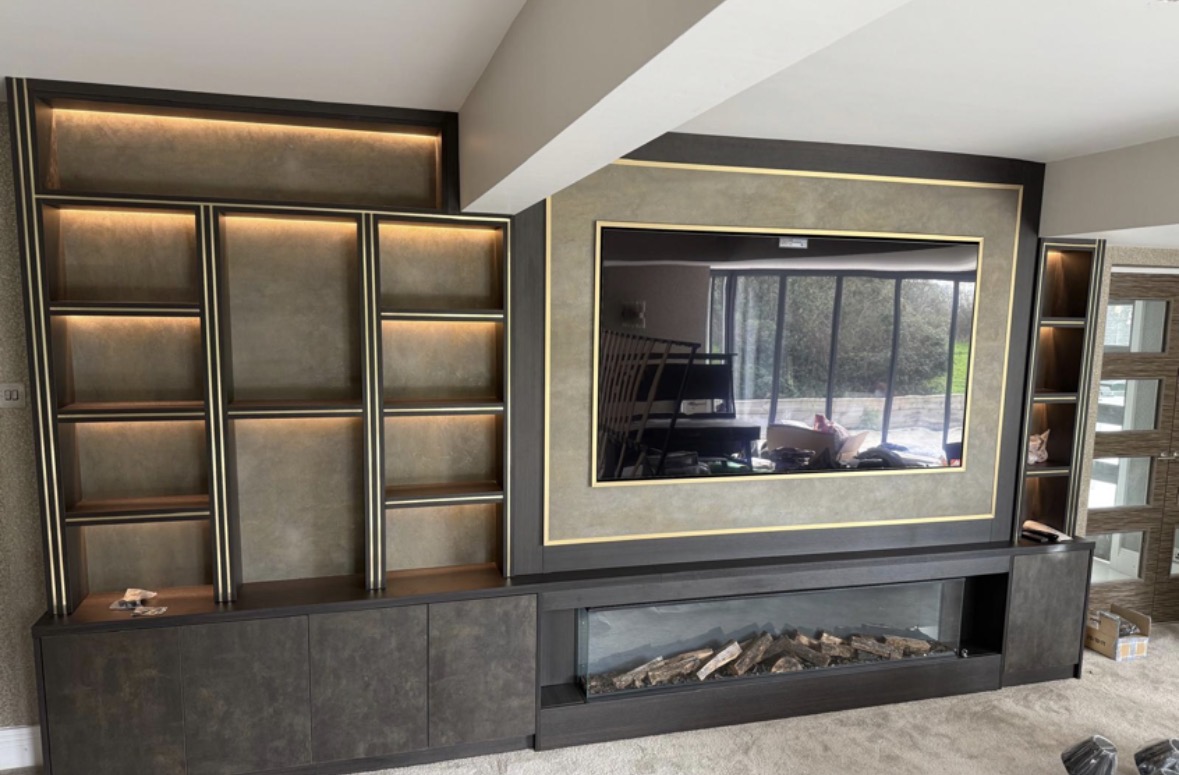 Media wall with LED-lit padded leather panels, a gold-framed television surround, long inset fire and low fitted cabinets