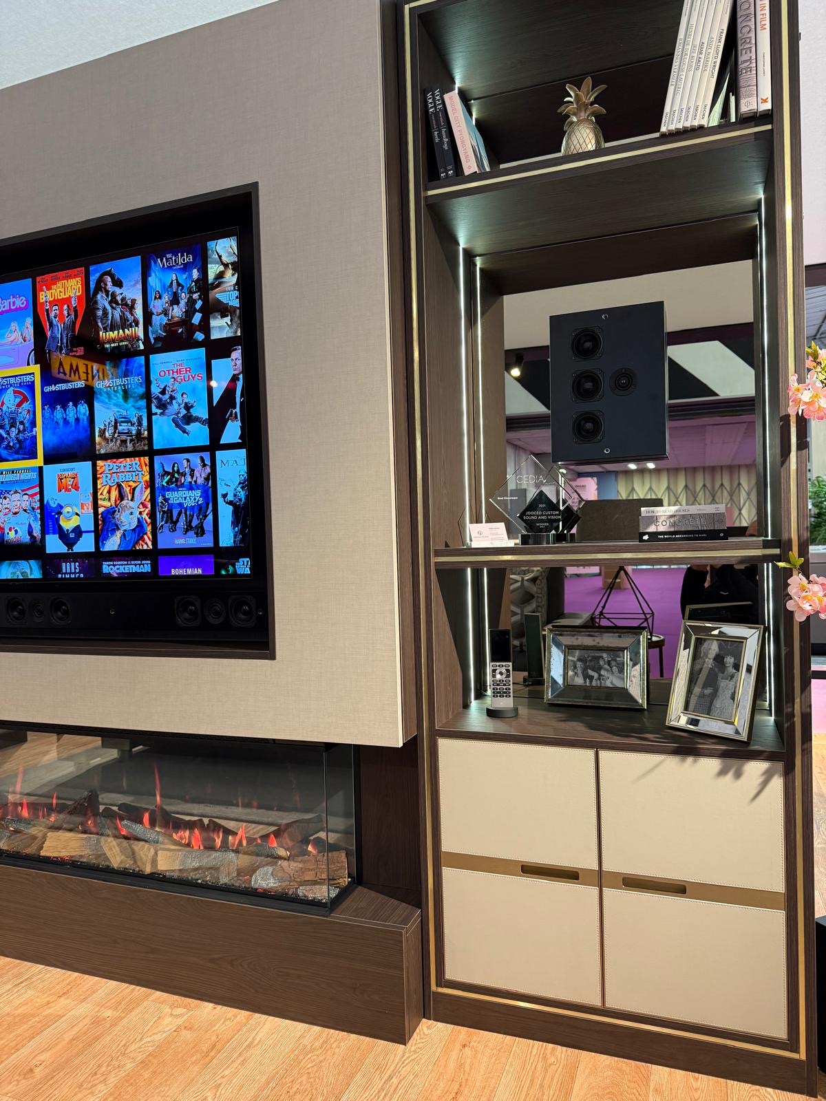 Bespoke media wall with a fabric-panelled television recess, linear electric fire and cream leather-fronted display cabinet