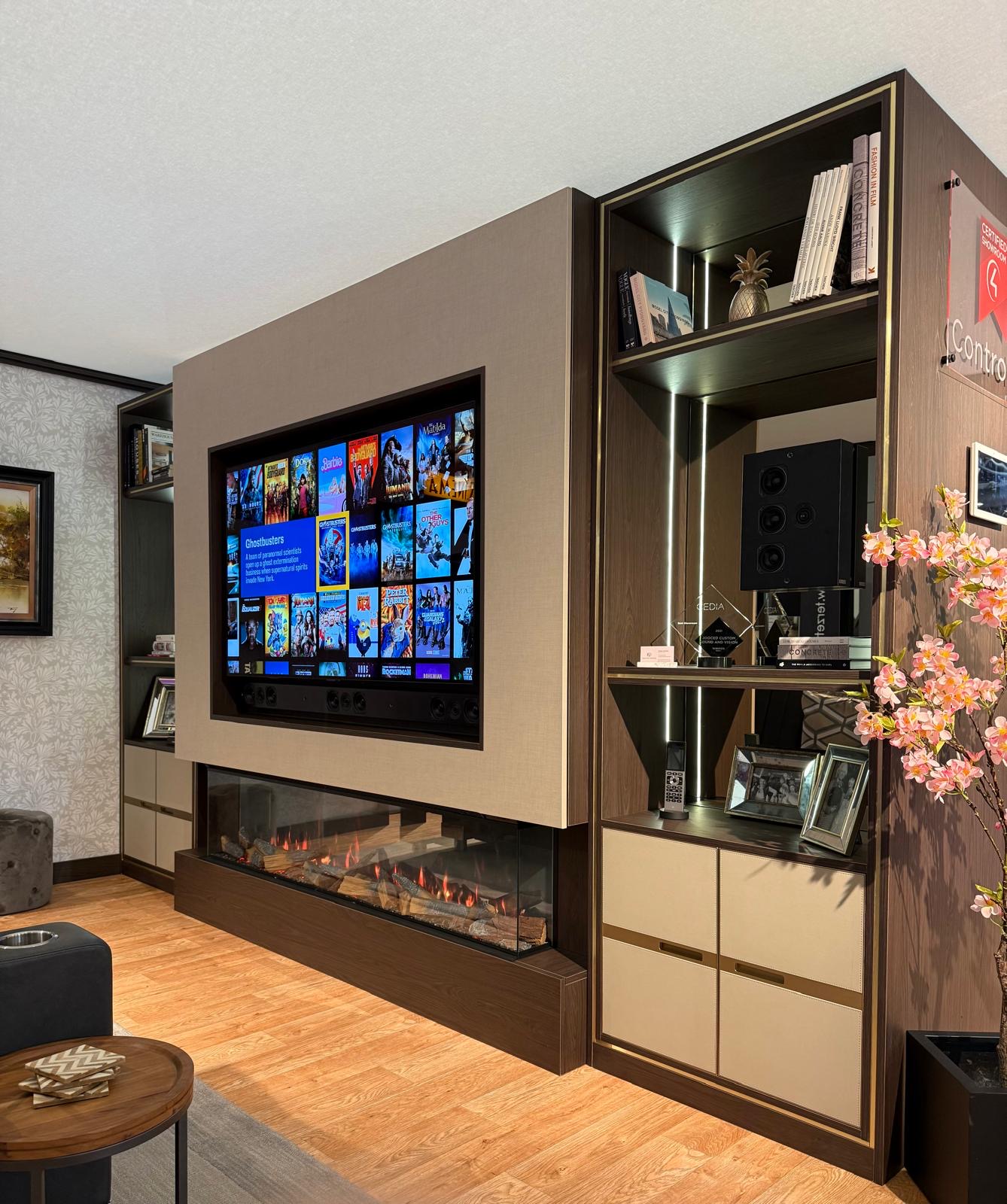 Full bespoke media wall with a recessed television, wide inset electric fire and tall dark oak display cabinetry with brass inlay