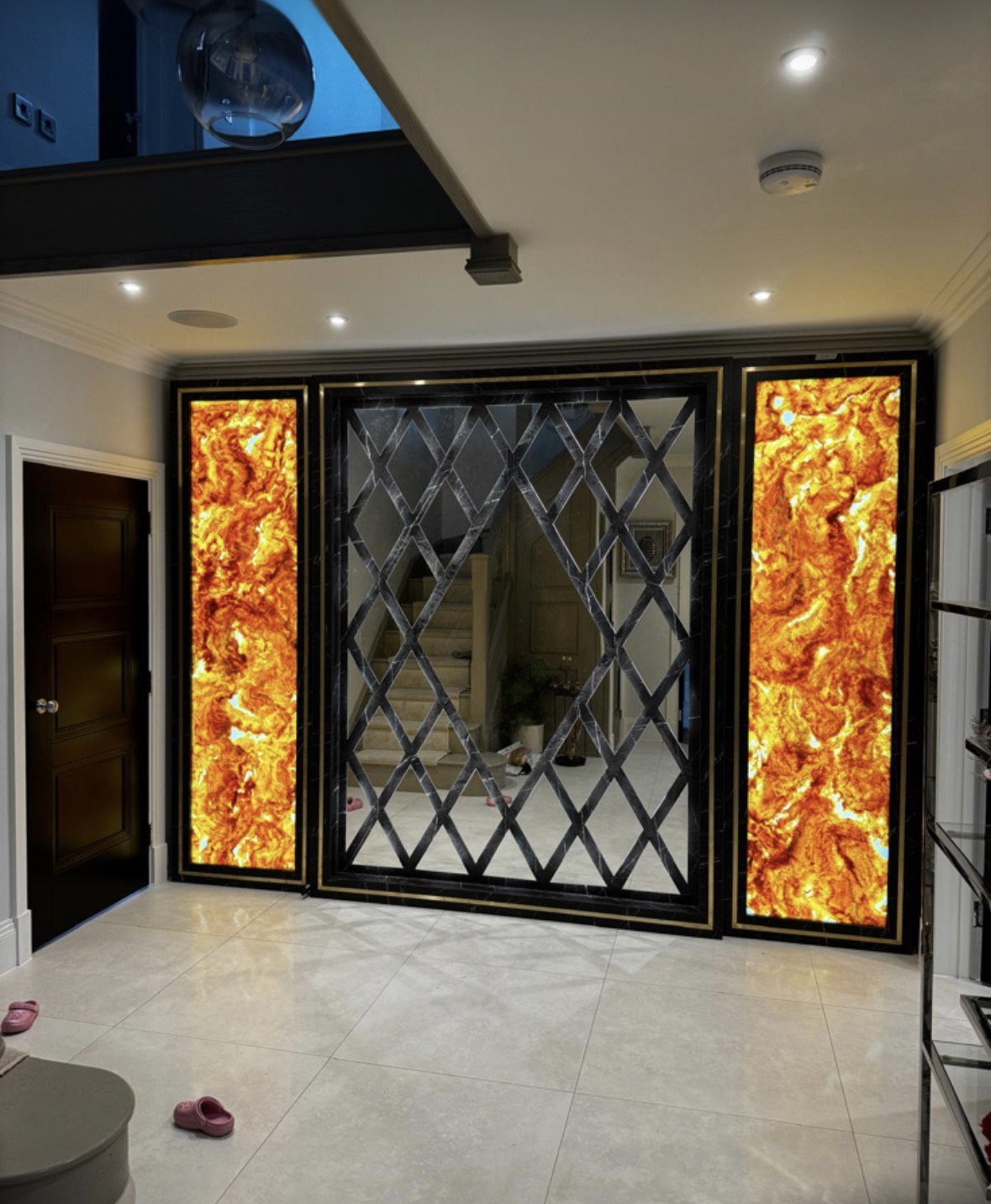 Room divider with backlit onyx-effect panels either side of a dark metal and glass screen