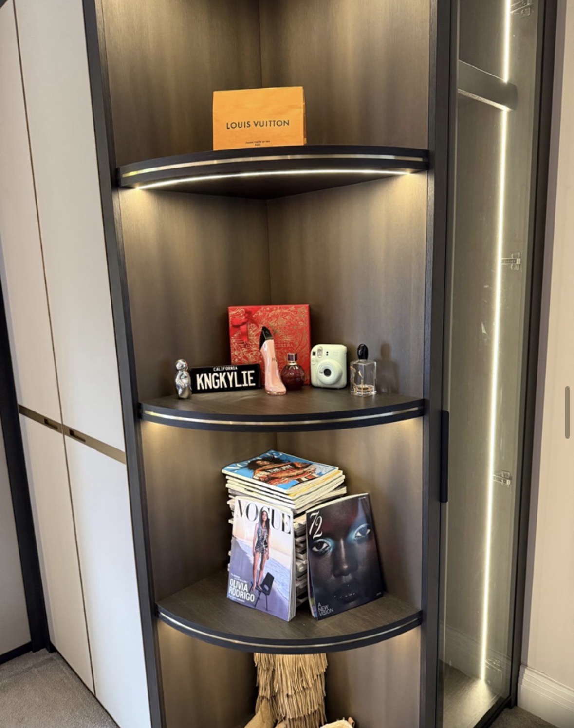 Curved LED-lit dressing room shelving in bronze and black, holding handbags, books and accessories