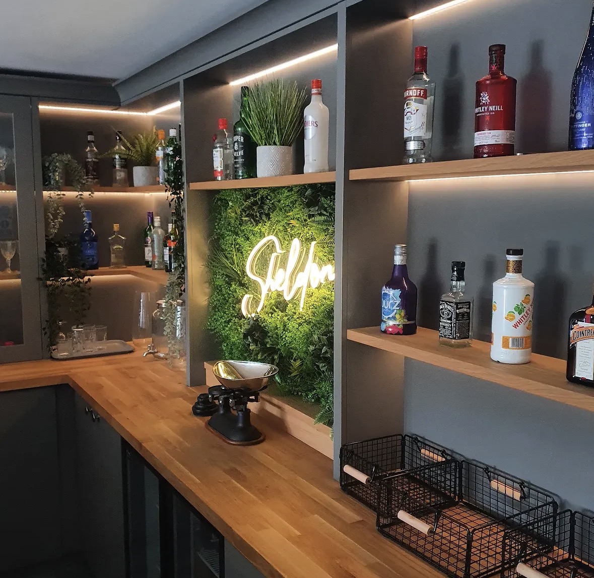 Bespoke home bar with solid oak worktop, illuminated oak display shelving and a living-wall feature panel