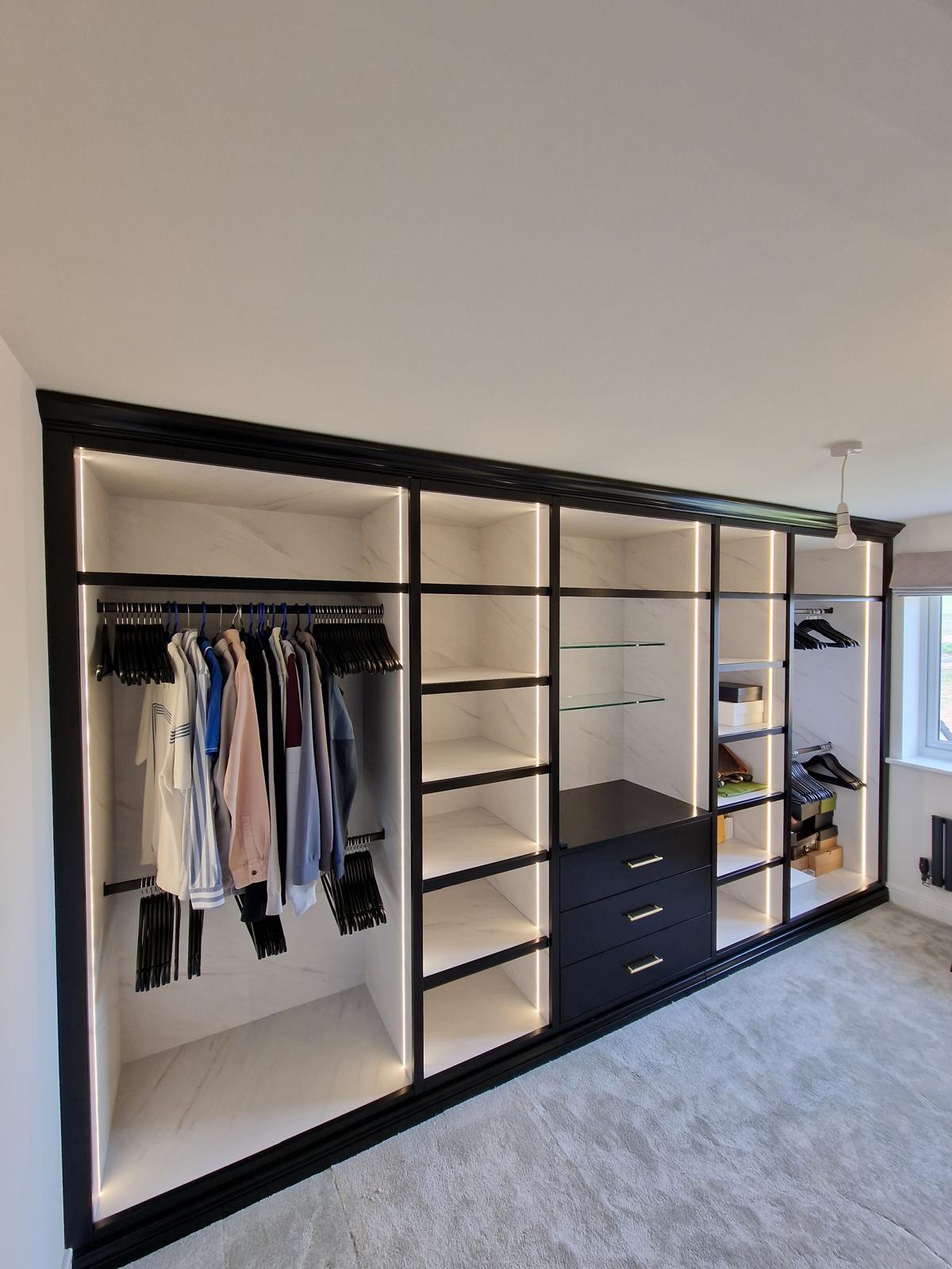 Walk-in wardrobe with marble-lined interior, LED-lit hanging rails, drawers and open shoe shelving
