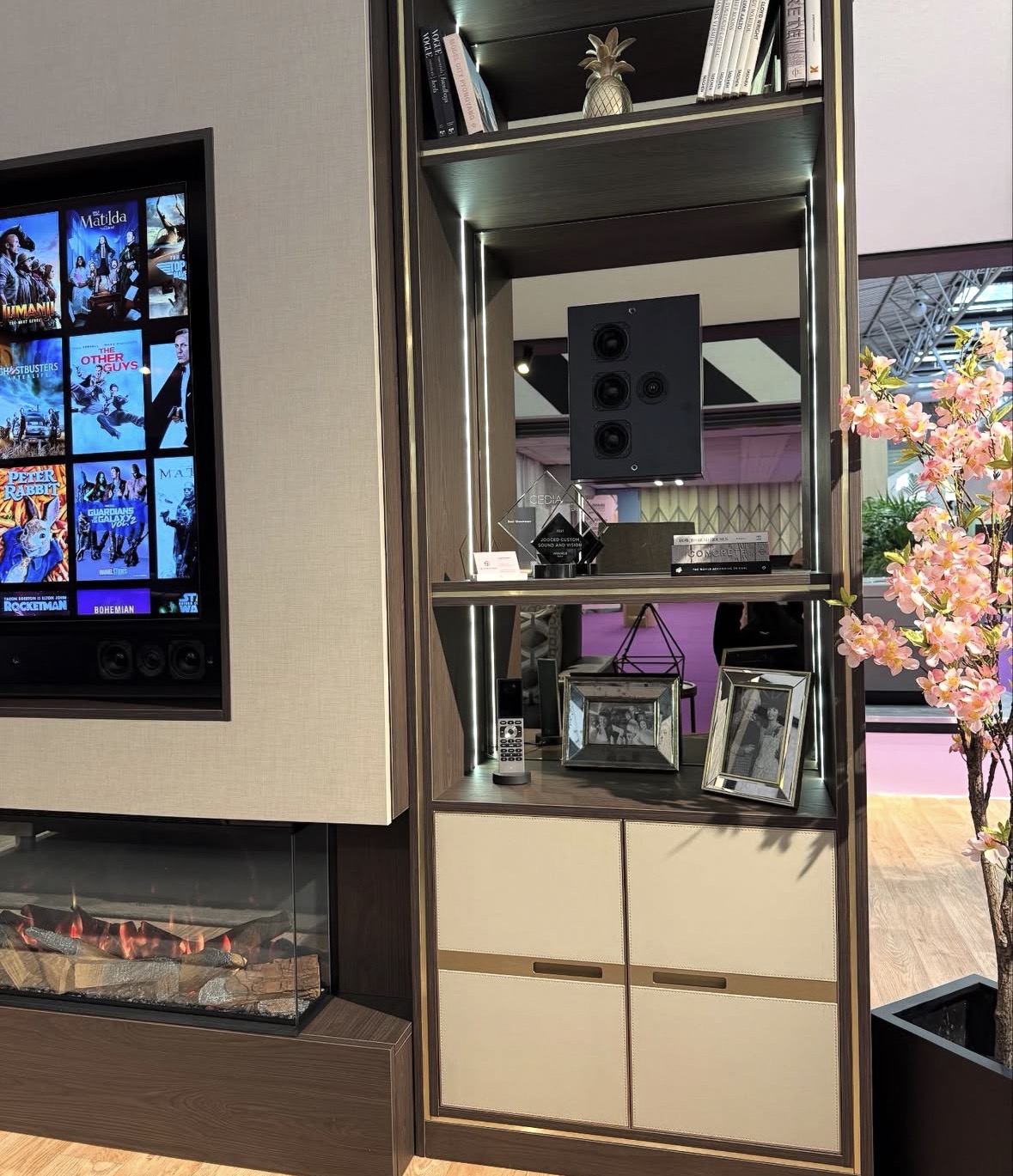 Lit walnut display shelving with brass trim and cream leather cabinet doors, part of a bespoke media wall