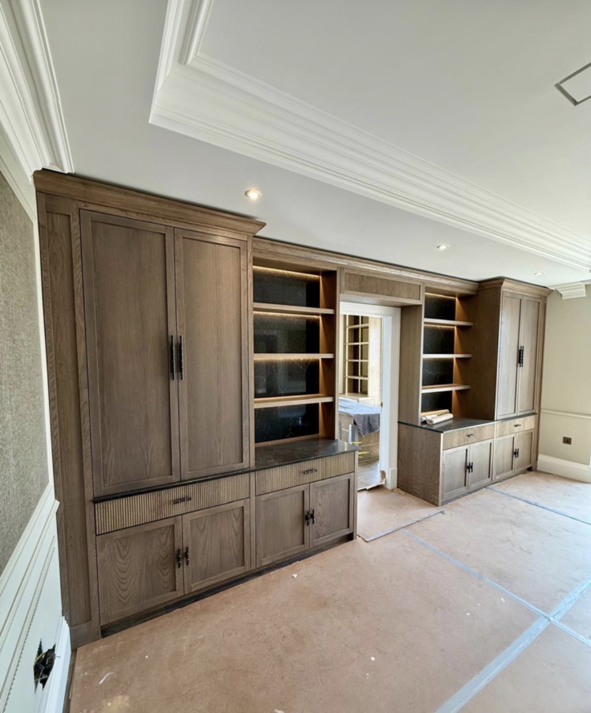 Tall oak dresser with panelled doors and open shelving, alongside a run of matching fitted base cabinets
