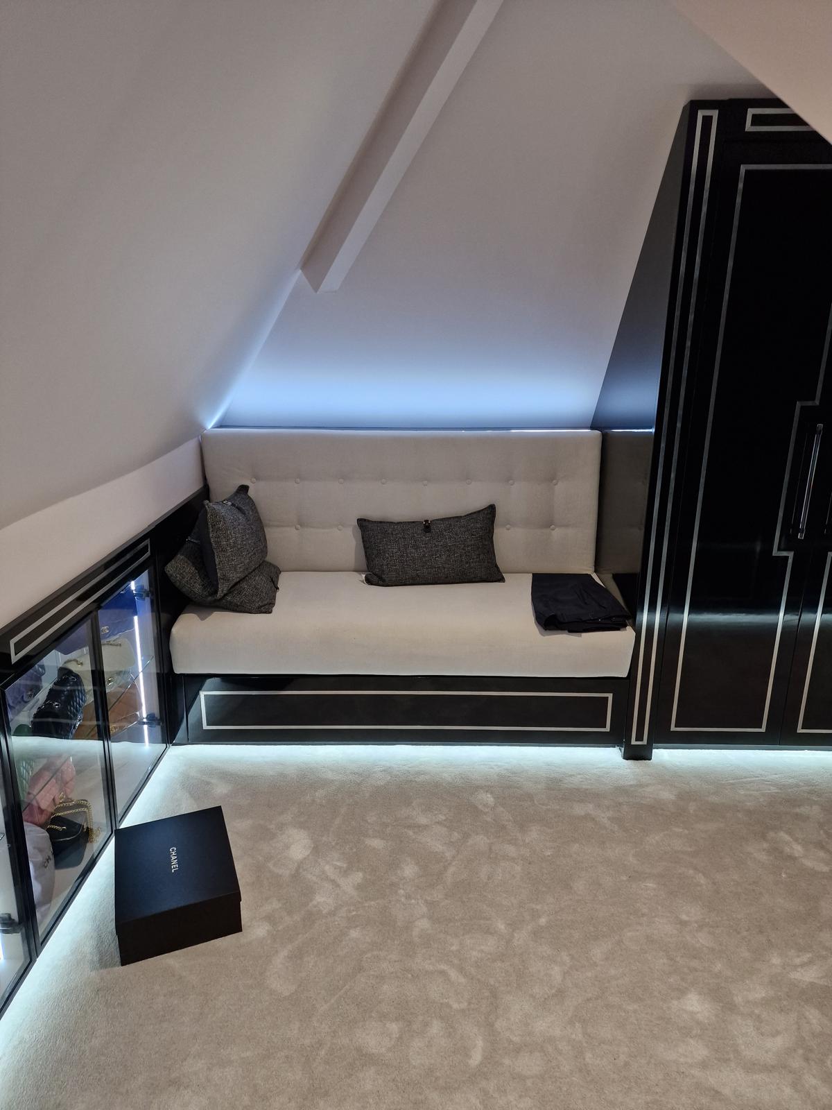 Loft dressing room with an upholstered built-in seat, concealed lighting and a lit glazed handbag display cabinet