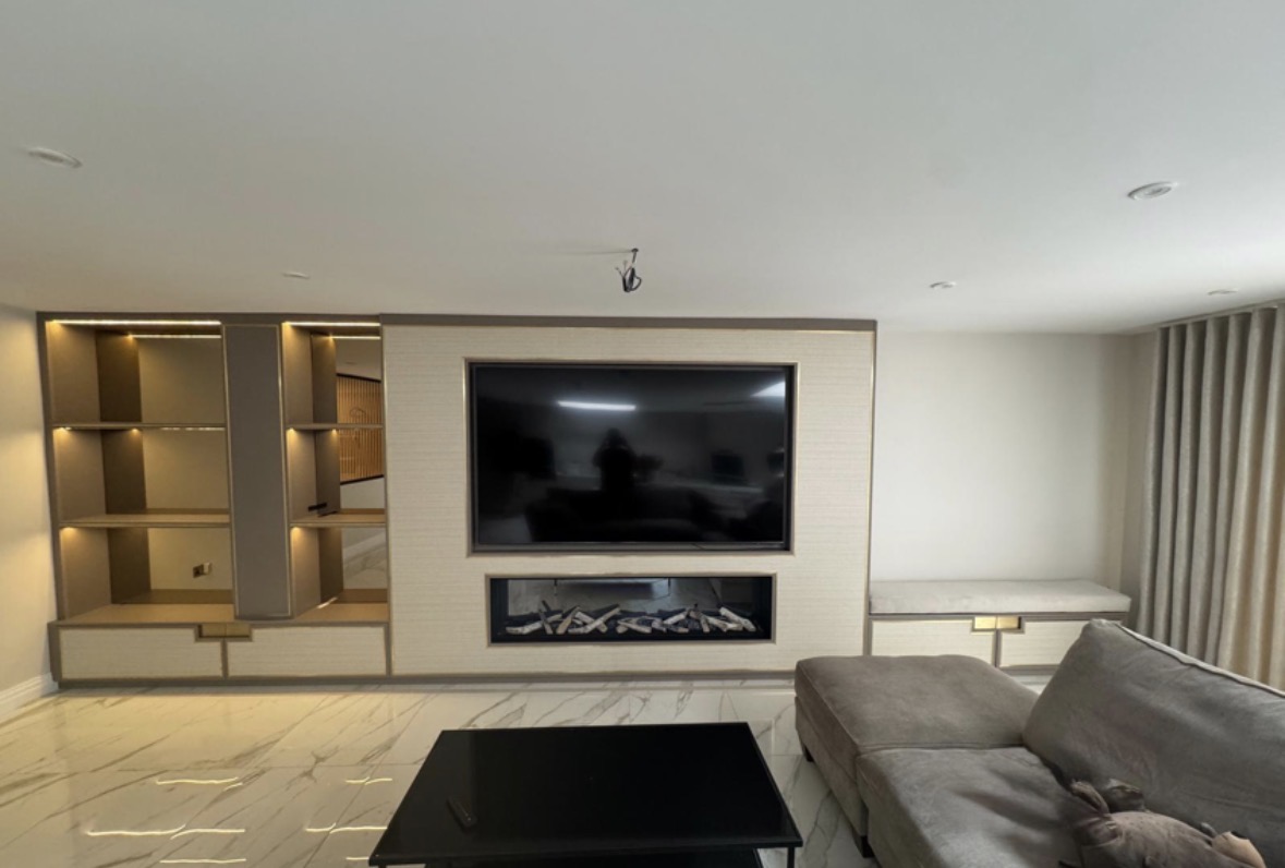Living room media wall with a stone-effect surround, long inset fire, recessed television and LED-lit display shelving