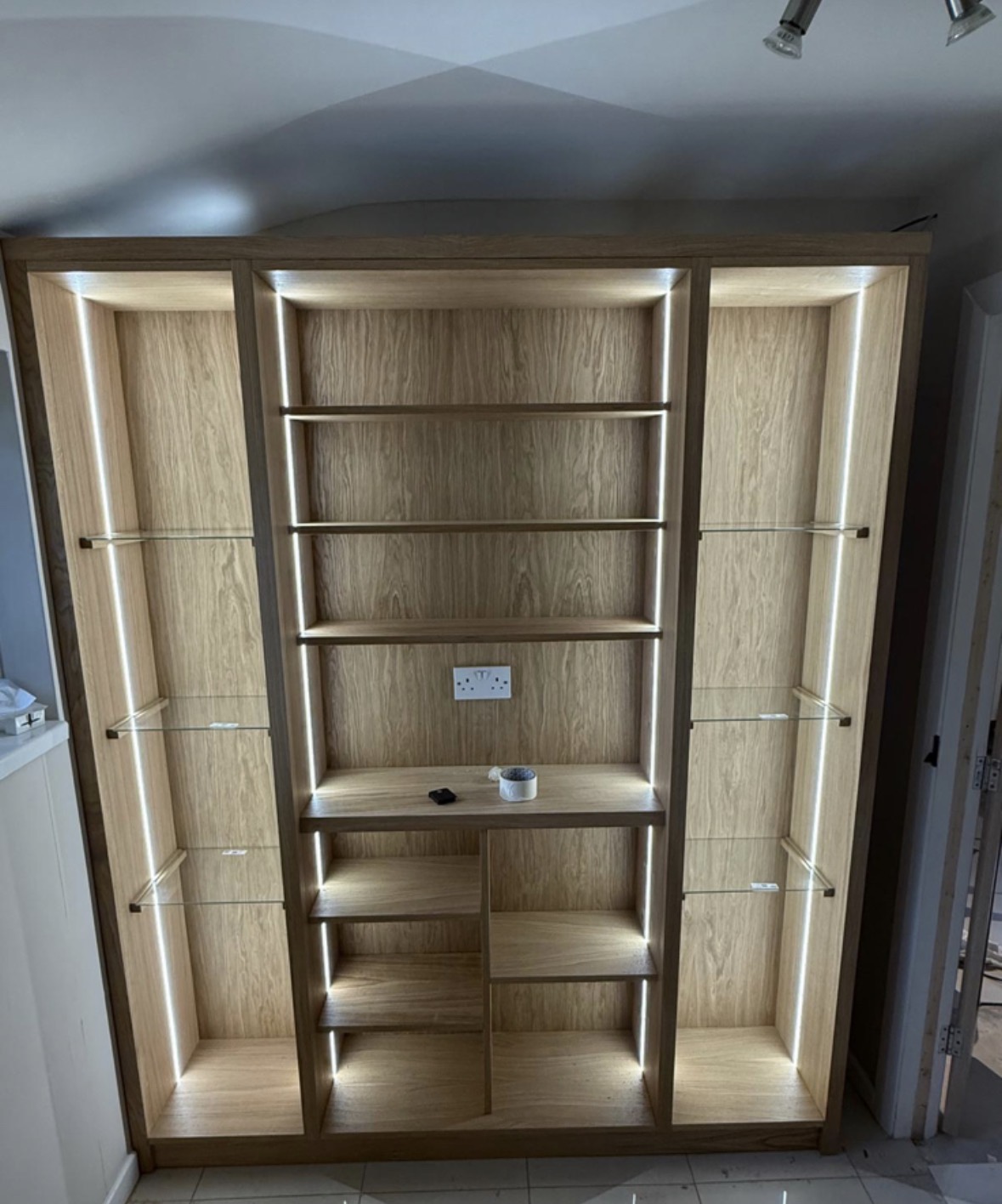 Fitted oak display unit with LED-lit glass shelves, open cubbies and a central work surface