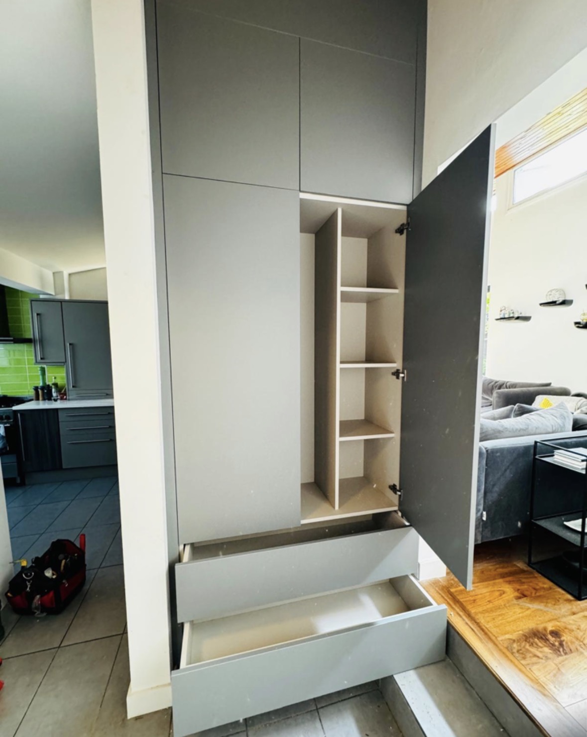 Tall fitted cupboard opened to show adjustable shelving and a deep pull-out drawer