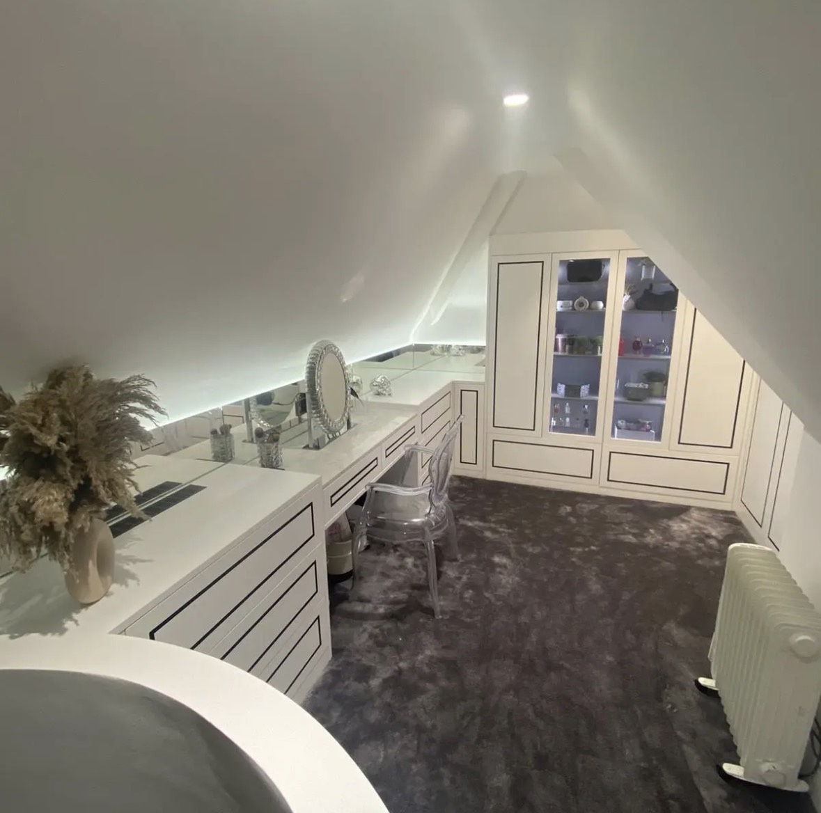Bespoke loft dressing room with a fitted dressing table, drawer banks and wardrobes following the pitched ceiling