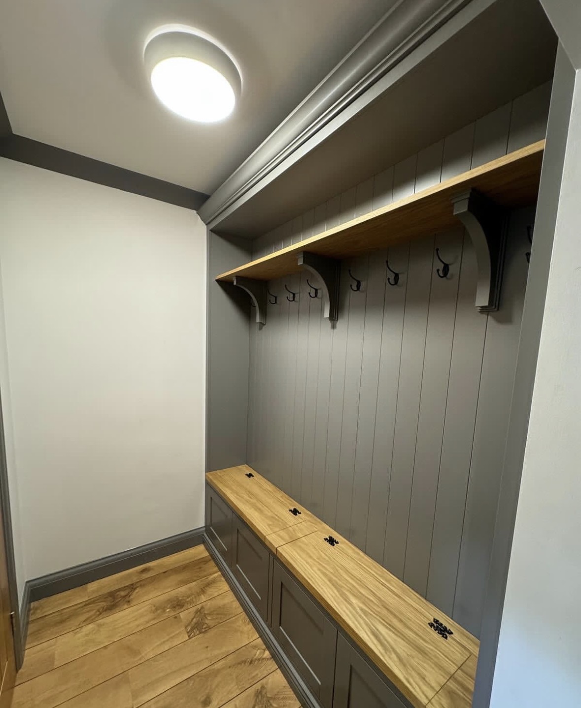 Fitted boot room in grey painted tongue-and-groove with solid oak bench seat, coat hooks and oak shelf
